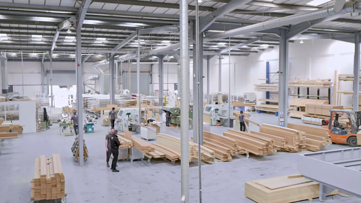 The Skirting World workshop in Birmingham, with stacks of machined MDF boards and moulding machines.